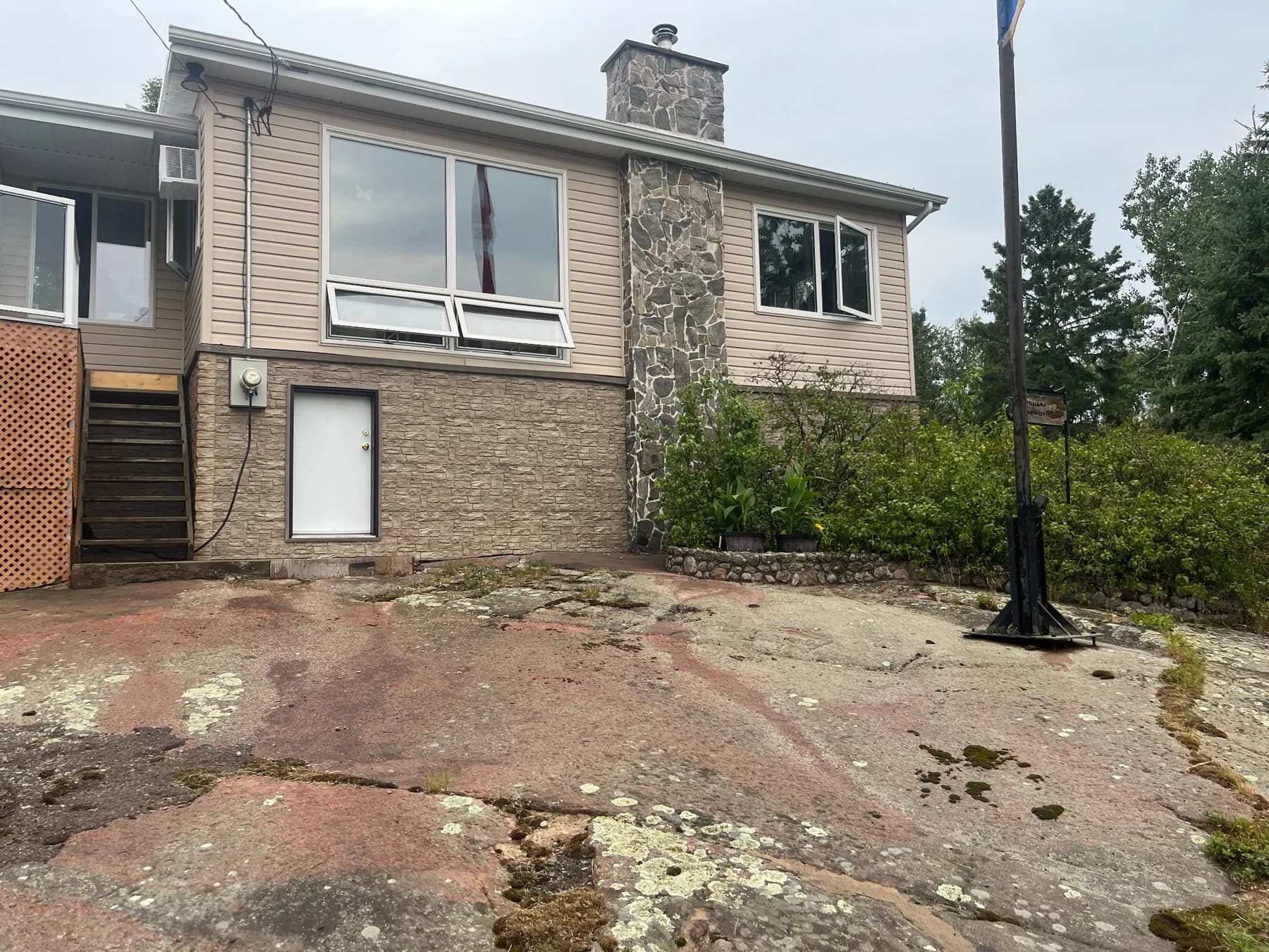 Exterior siding installation on a Whiteshell Provincial Park cabin with stone chimney and exposed Canadian Shield granite
