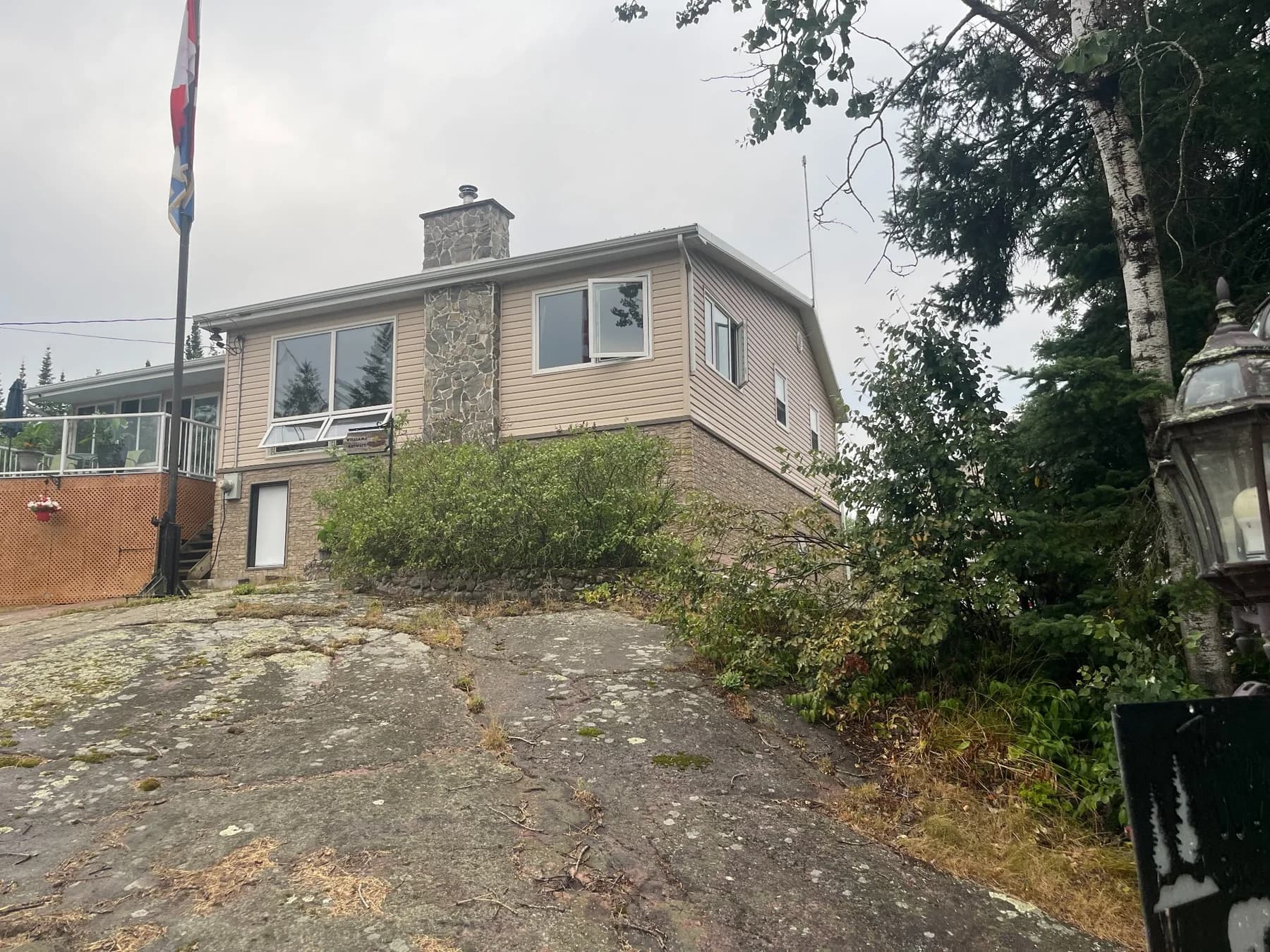 Whiteshell cabin exterior showing new siding surrounded by mature trees and exposed granite